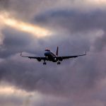 A low angle shot of an airplane descending from a clouded sky